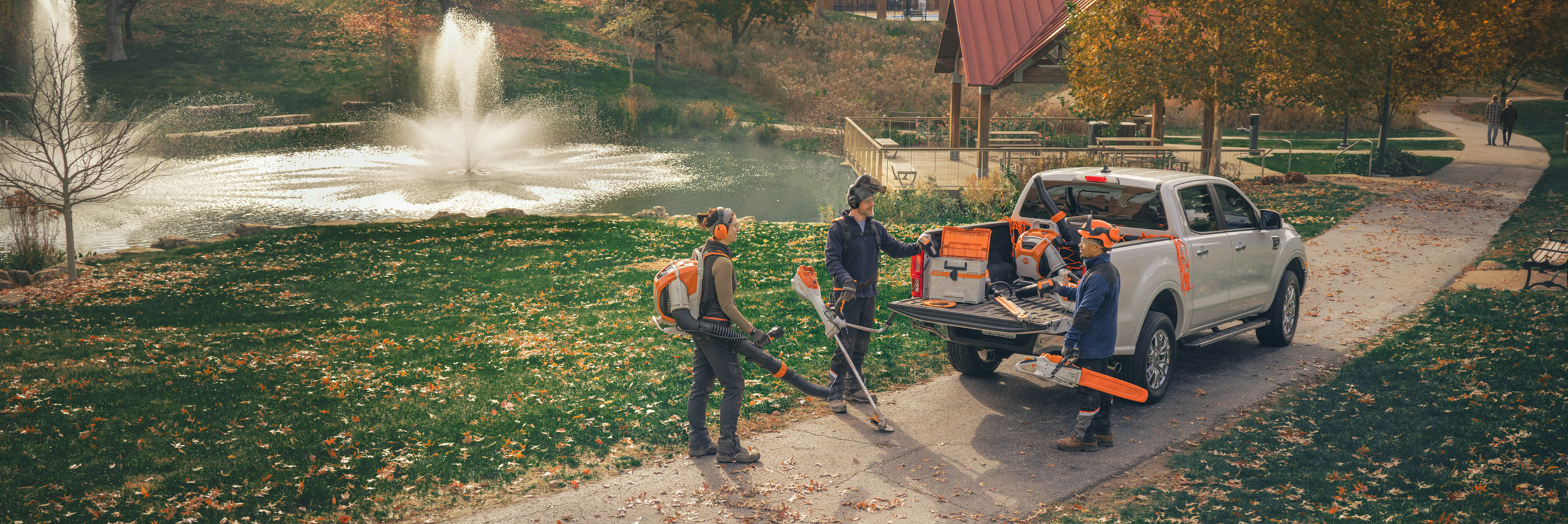 Grupa profesionalnih vrtlara stoji oko svojih vozila i priprema se za rad sa STIHL baterijskim uređajima.