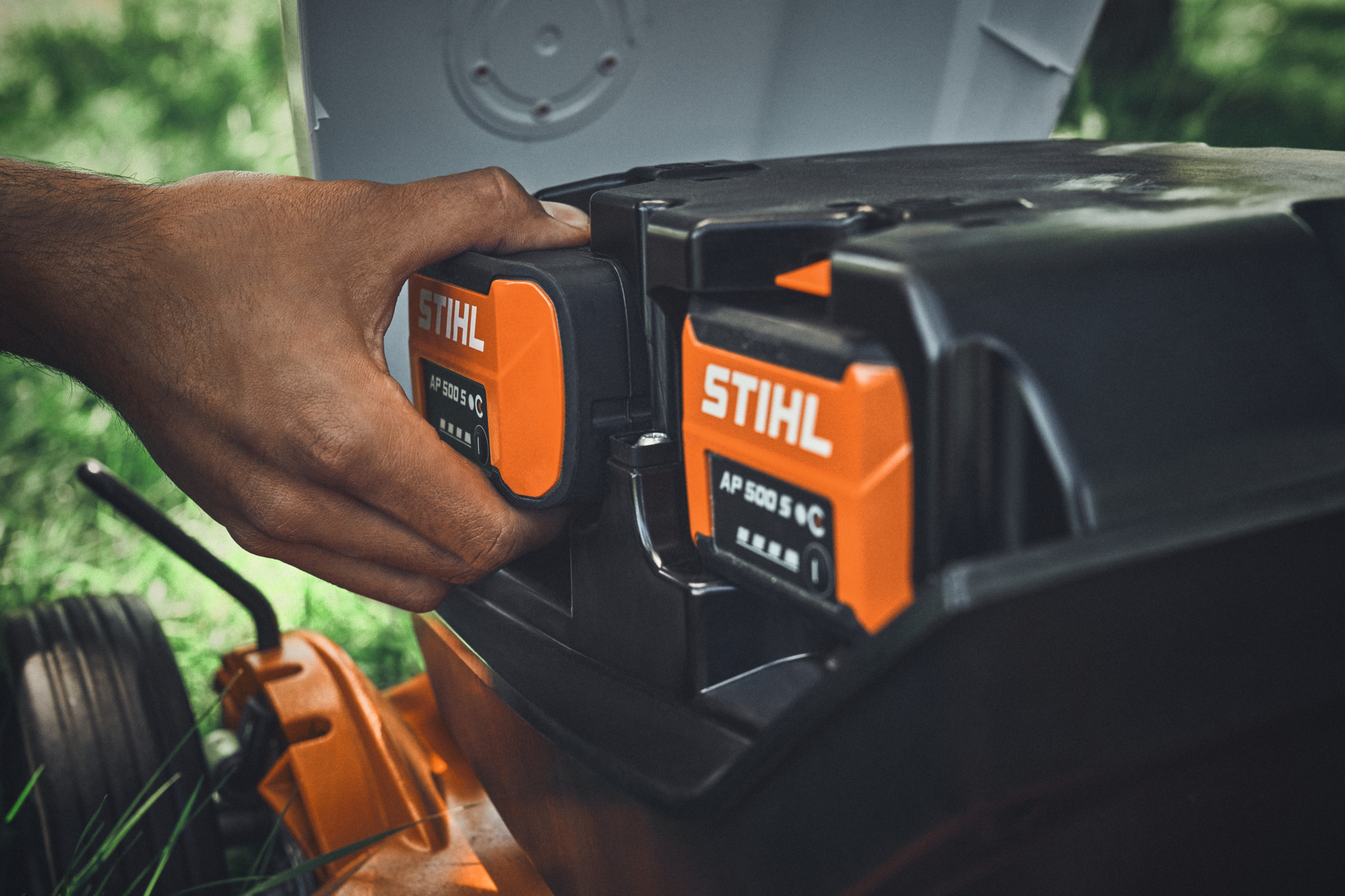 Osoba postavlja bateriju STIHL AP 500 S u STIHL baterijsku kosačicu