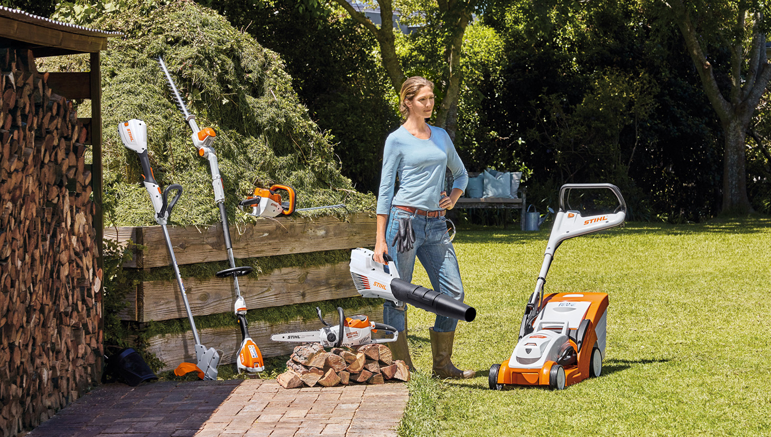 Žena stoji u bašti sa izborom baterijskih proizvoda kompanije STIHL