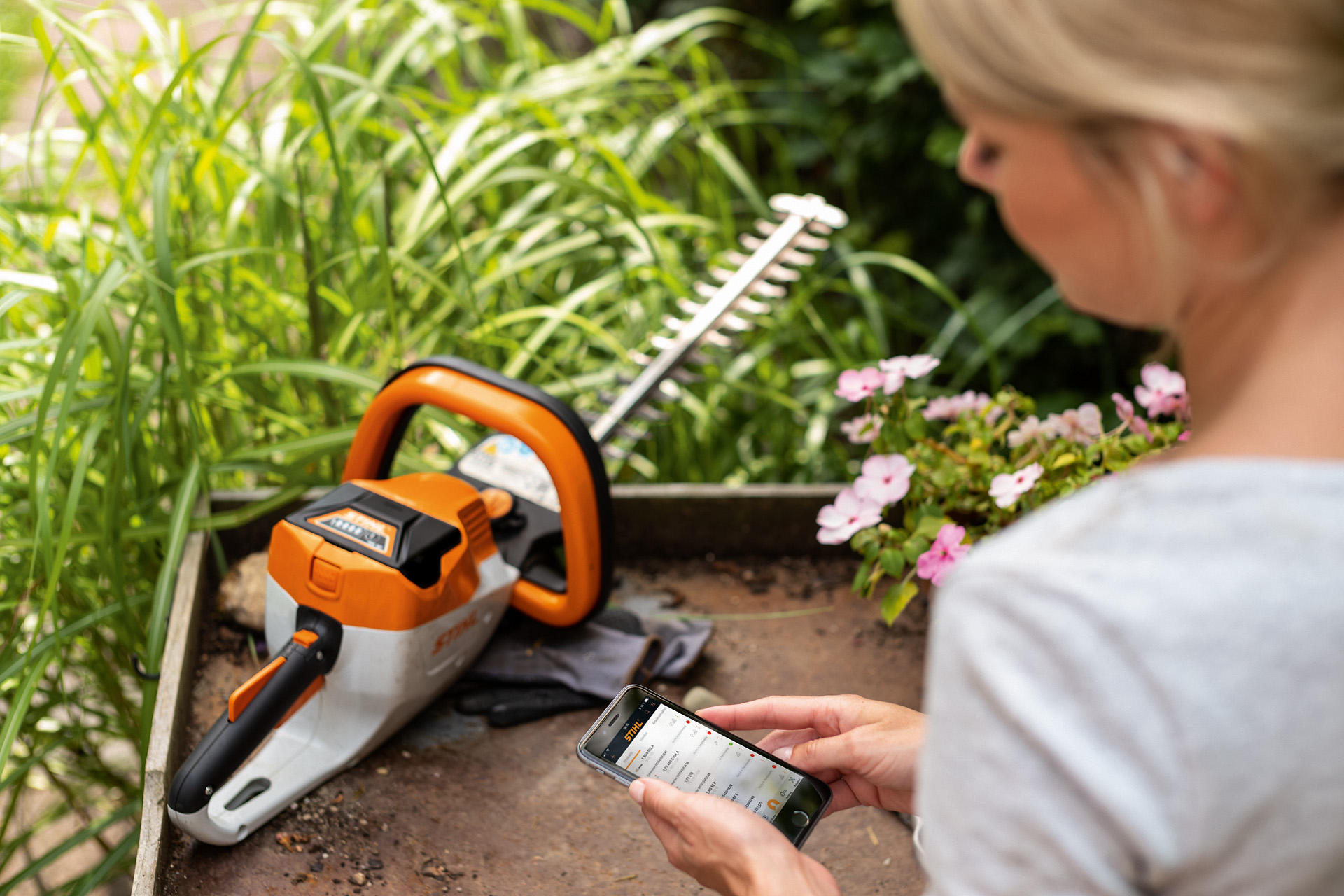 Žena registruje STIHL trimer za rezanje žive ograde pomoću STIHL aplikacije na pametnom telefonu