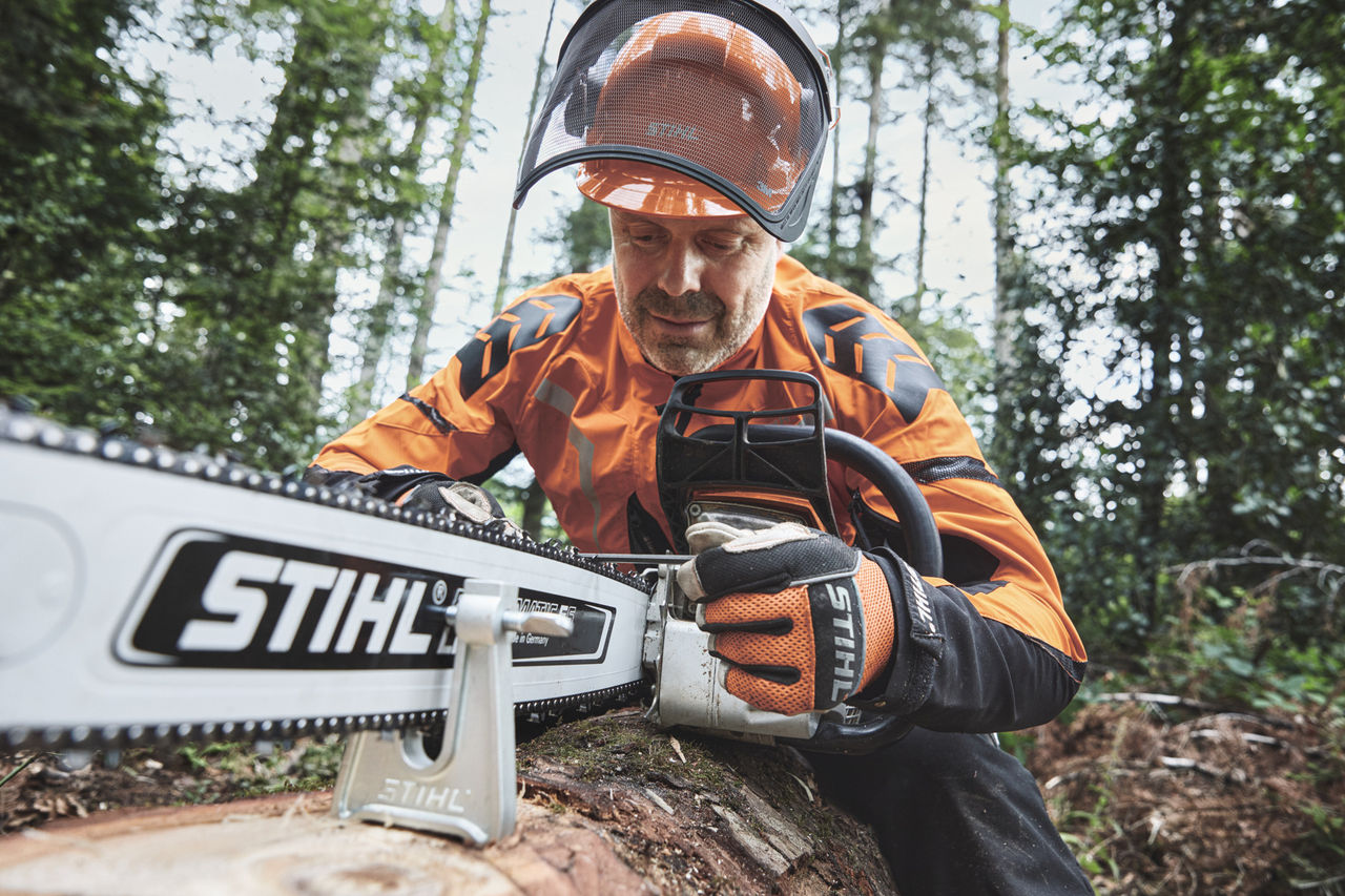Čovek u zaštitnoj opremi radi pomoću STIHL motorne testere u šumi